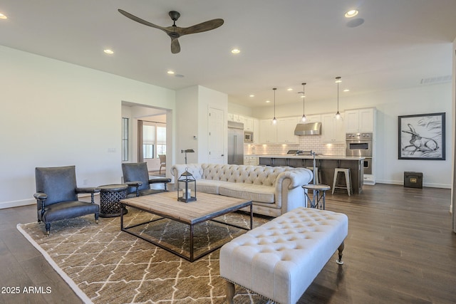 living room with ceiling fan and dark hardwood / wood-style flooring