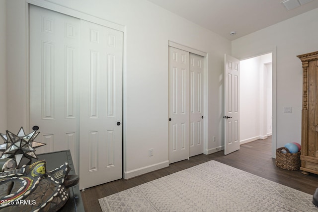 bedroom featuring multiple closets and dark hardwood / wood-style floors