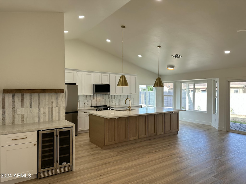 kitchen with wine cooler, stainless steel appliances, white cabinetry, and a large island