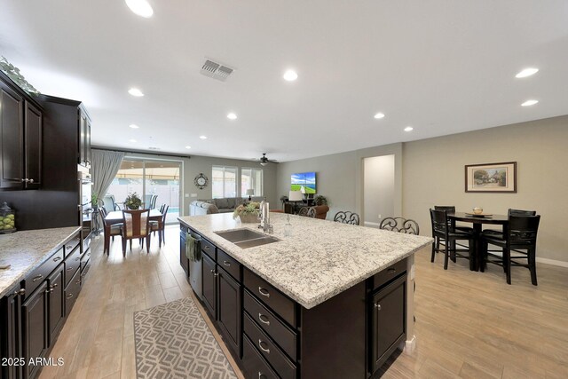 3359 E Penedes Dr, Gilbert, AZ 85298 - kitchen with a sink, light wood-style flooring, recessed lighting, an island with sink, and light stone counters