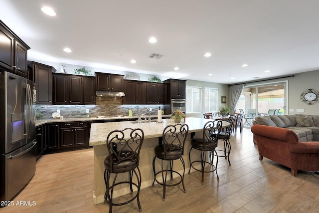 3359 E Penedes Dr, Gilbert, AZ 85298 - kitchen with appliances with stainless steel finishes, open floor plan, a sink, under cabinet range hood, and tasteful backsplash