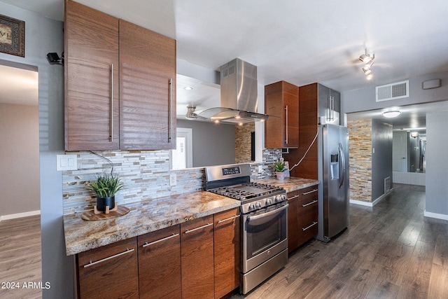 kitchen featuring dark wood finished floors, stainless steel appliances, visible vents, backsplash, and ventilation hood