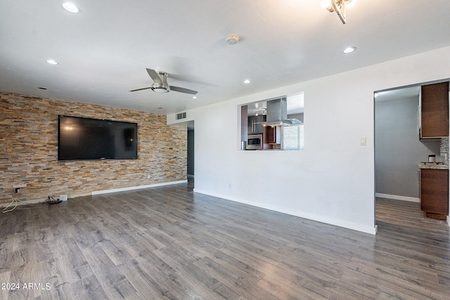 unfurnished living room featuring a ceiling fan, visible vents, baseboards, and wood finished floors