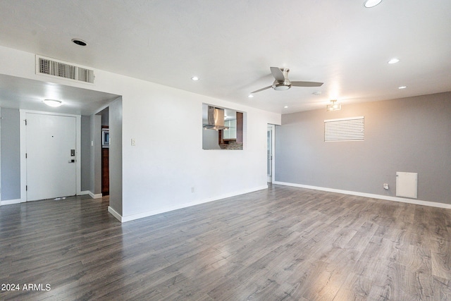 empty room with ceiling fan, wood finished floors, visible vents, and baseboards