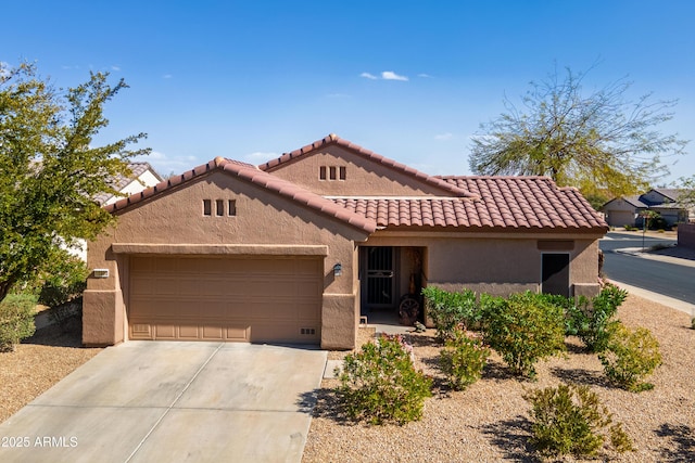 view of front facade with a garage, a tile roof, concrete driveway, and stucco siding