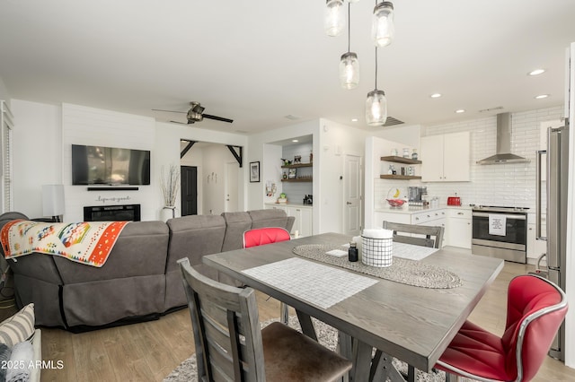 dining space featuring a large fireplace, light wood-style flooring, and recessed lighting