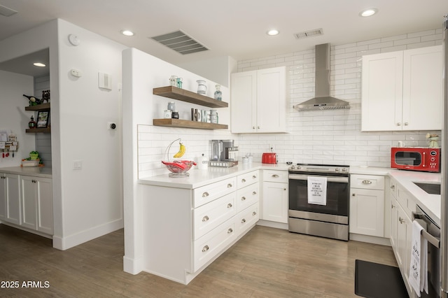 kitchen with appliances with stainless steel finishes, backsplash, visible vents, and wall chimney range hood