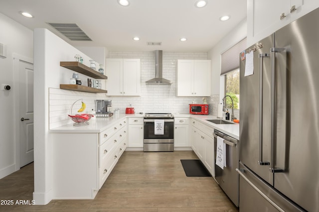 kitchen with a sink, appliances with stainless steel finishes, wall chimney range hood, and visible vents