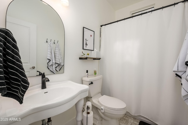 bathroom featuring toilet, curtained shower, and a sink