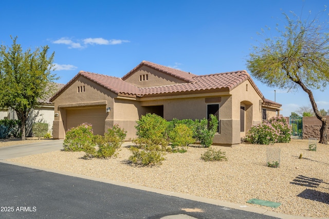 mediterranean / spanish-style home featuring a garage, driveway, a tiled roof, and stucco siding