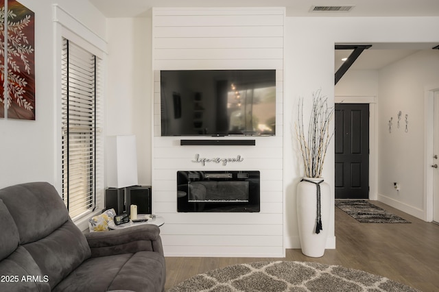 living area featuring baseboards, a fireplace, visible vents, and wood finished floors