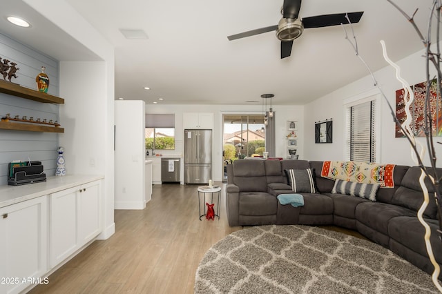 living area featuring light wood-style flooring, a ceiling fan, and recessed lighting