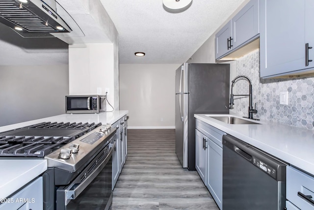 425 Paseo Redondo Unit 6L, Tucson, AZ 85701 - kitchen with stainless steel appliances, ventilation hood, light countertops, backsplash, and light wood-style floors