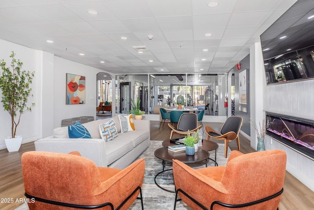 425 Paseo Redondo Unit 6L, Tucson, AZ 85701 - living area featuring light wood-style floors, a glass covered fireplace, arched walkways, recessed lighting, and a paneled ceiling