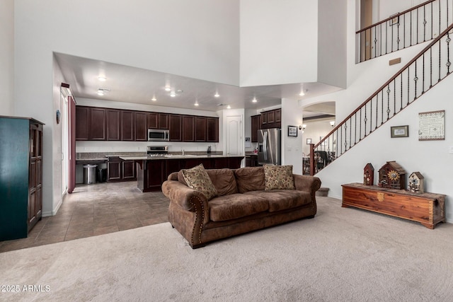 4125 W Lydia Ln, Phoenix, AZ 85041 - living area with arched walkways, stairs, a towering ceiling, and light colored carpet