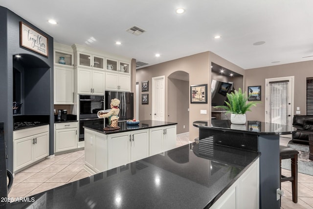 kitchen featuring a kitchen island, white cabinetry, appliances with stainless steel finishes, and light tile patterned flooring