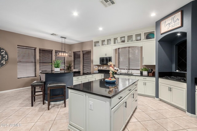 kitchen featuring sink, decorative light fixtures, light tile patterned floors, a kitchen island, and white cabinets