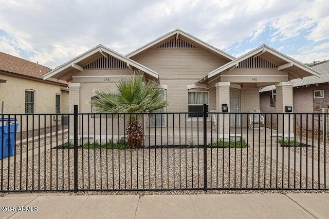 craftsman-style house with a fenced front yard and brick siding