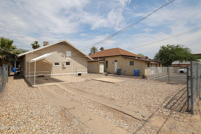 rear view of property with central air condition unit, fence, and stucco siding