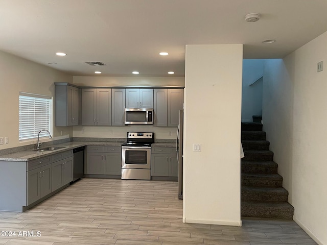 kitchen featuring stone counters, gray cabinetry, sink, and stainless steel appliances