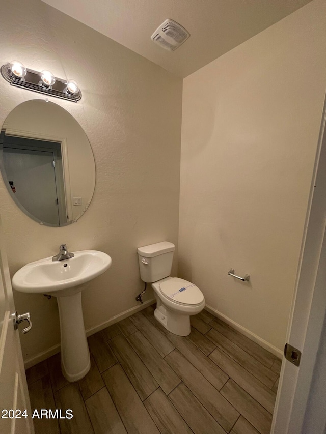 bathroom with toilet and hardwood / wood-style floors