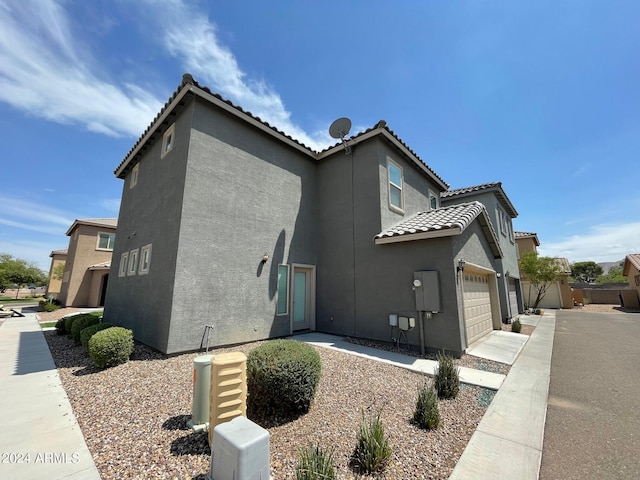 view of home's exterior with a garage, a tile roof, concrete driveway, and stucco siding