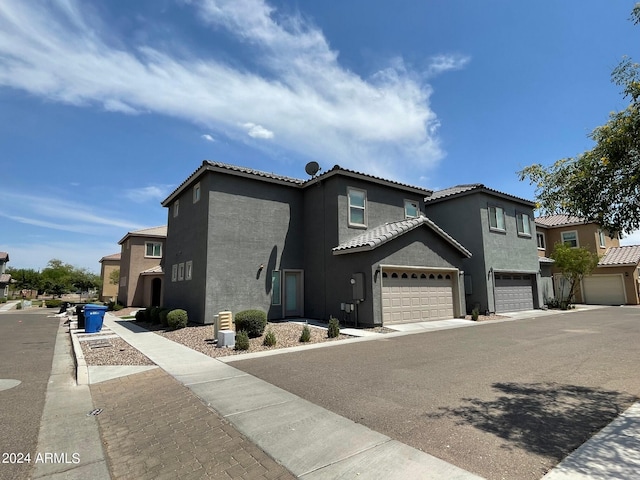 view of front of home with a garage, a tile roof, and stucco siding