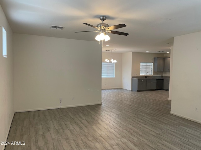 unfurnished living room with sink, ceiling fan with notable chandelier, and hardwood / wood-style floors