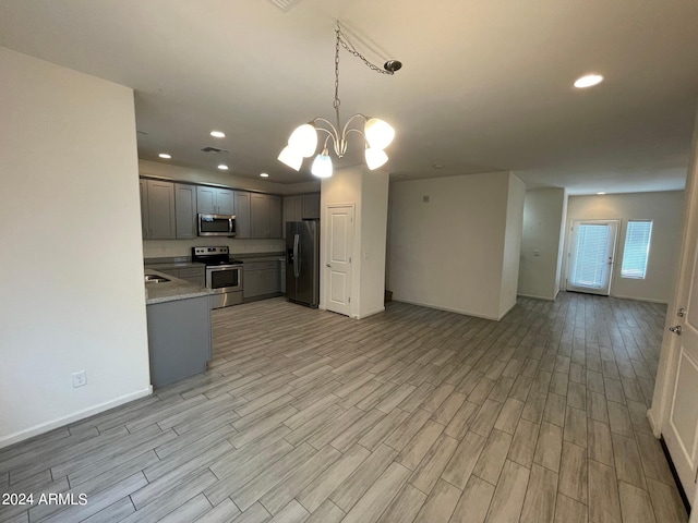 kitchen with stainless steel appliances, a chandelier, pendant lighting, and light hardwood / wood-style floors