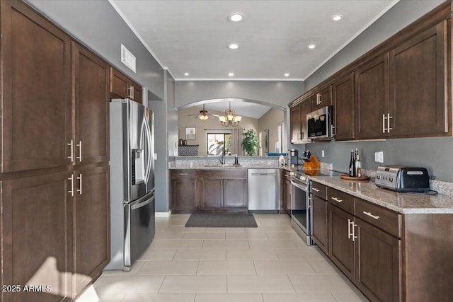 kitchen with visible vents, arched walkways, light stone countertops, stainless steel appliances, and a sink