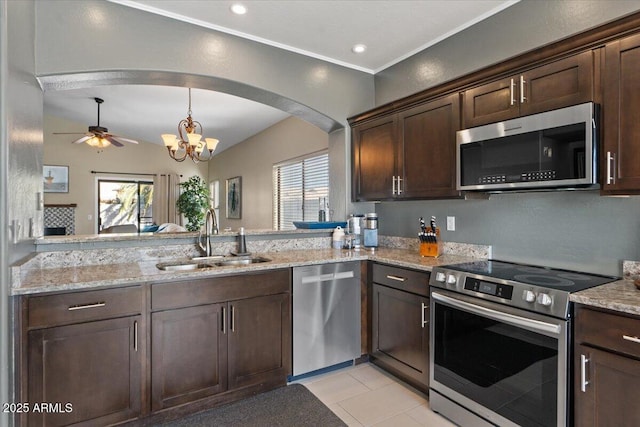 kitchen with stainless steel appliances, dark brown cabinets, a sink, and light stone counters