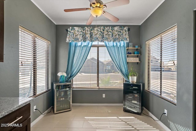 dining room featuring baseboards, ceiling fan, wine cooler, crown molding, and light tile patterned flooring