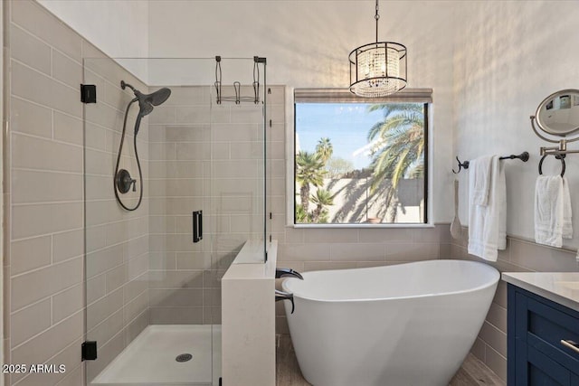 bathroom featuring a freestanding tub, a shower stall, vanity, and tile walls