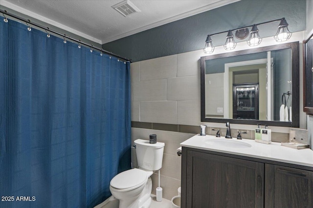 bathroom featuring visible vents, toilet, ornamental molding, vanity, and tile walls