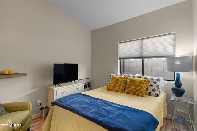 bedroom with vaulted ceiling, wood finished floors, and baseboards