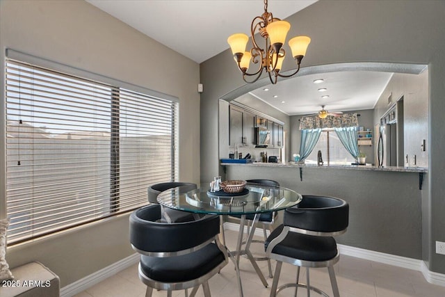 dining area featuring arched walkways, light tile patterned floors, ceiling fan with notable chandelier, and baseboards