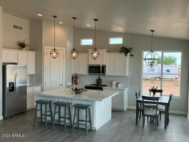 kitchen featuring white cabinets, stainless steel appliances, a wealth of natural light, and an island with sink