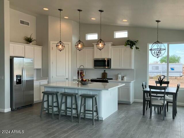 kitchen with appliances with stainless steel finishes, white cabinetry, a kitchen island with sink, and dark wood-type flooring