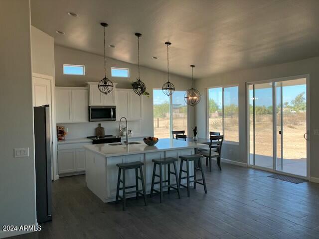 kitchen with a kitchen island with sink, white cabinets, sink, appliances with stainless steel finishes, and decorative light fixtures