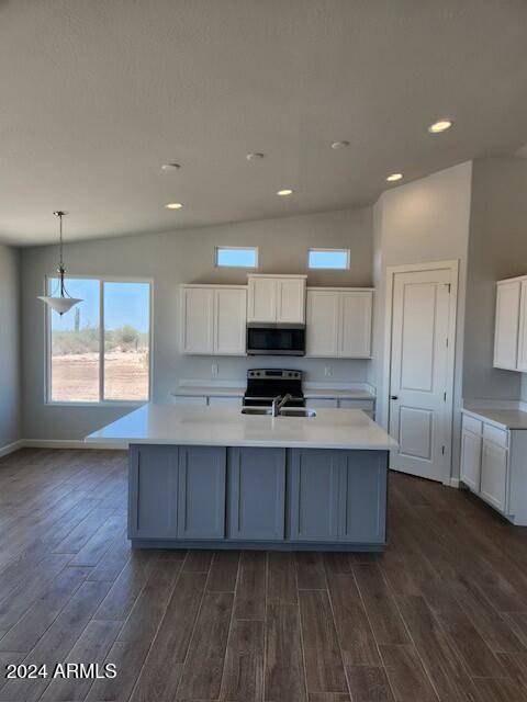 kitchen featuring appliances with stainless steel finishes, dark hardwood / wood-style flooring, a center island with sink, and hanging light fixtures