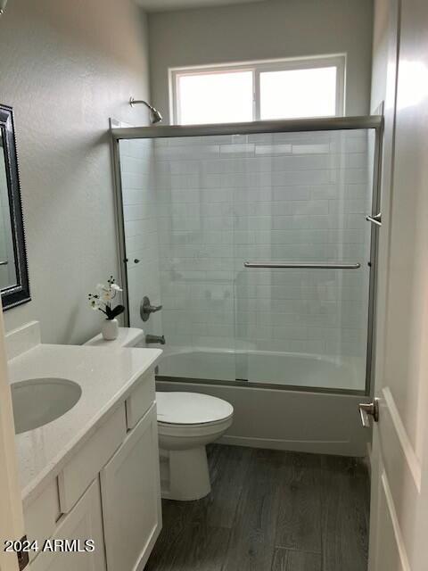 full bathroom featuring enclosed tub / shower combo, toilet, wood-type flooring, and vanity