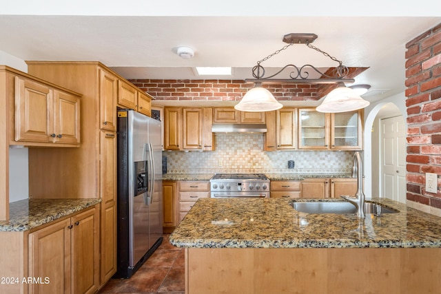 kitchen featuring stone counters, sink, hanging light fixtures, backsplash, and appliances with stainless steel finishes