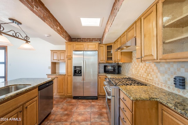 kitchen featuring pendant lighting, exhaust hood, a skylight, light stone counters, and stainless steel appliances