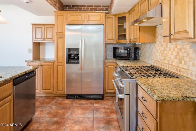 kitchen featuring light stone countertops, appliances with stainless steel finishes, tasteful backsplash, extractor fan, and dark tile patterned floors