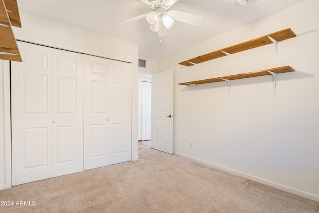 unfurnished bedroom featuring ceiling fan, a closet, light colored carpet, and a textured ceiling