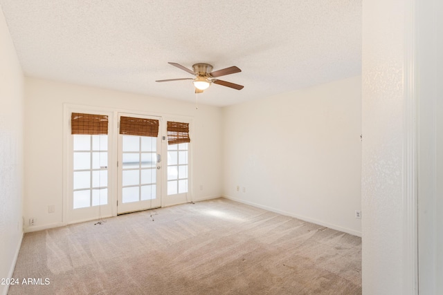 empty room featuring ceiling fan, light colored carpet, a textured ceiling, and french doors