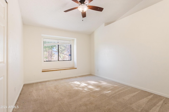 spare room with a textured ceiling, ceiling fan, light carpet, and vaulted ceiling