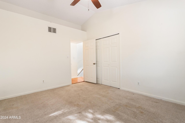 unfurnished bedroom with ceiling fan, a closet, high vaulted ceiling, and light colored carpet