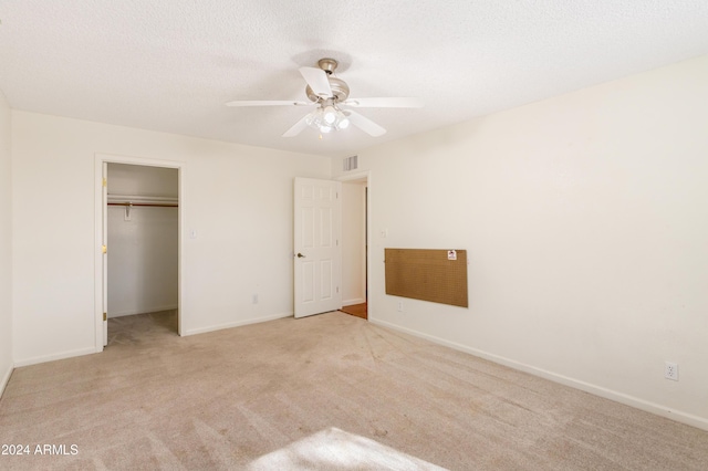 unfurnished bedroom featuring ceiling fan, a closet, light colored carpet, and a textured ceiling