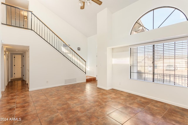 unfurnished living room featuring dark tile patterned flooring, ceiling fan, and high vaulted ceiling